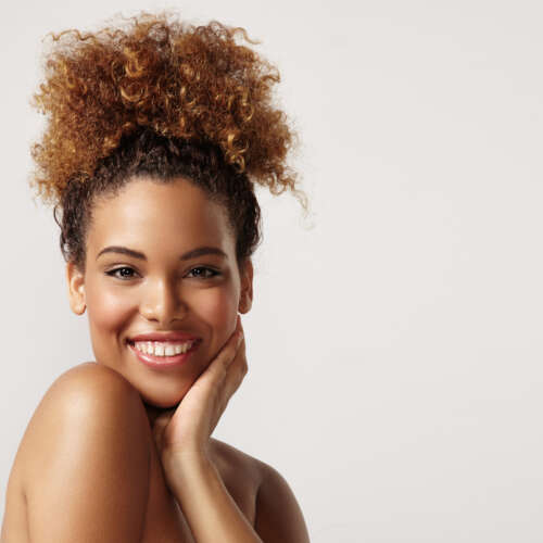 woman smiling leaning her left hand against her face