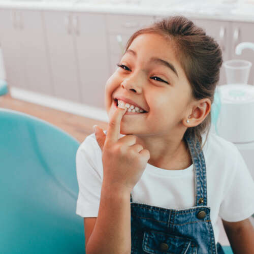 girl showing her teeth in dentist chair