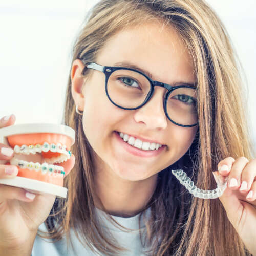 girl smiling holding dentures