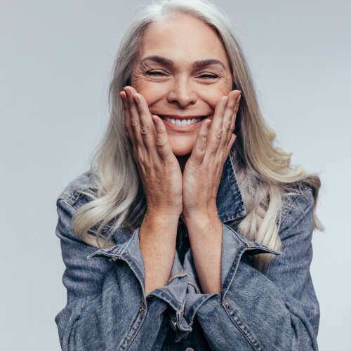 blonde women with white teeth smiling holding her face