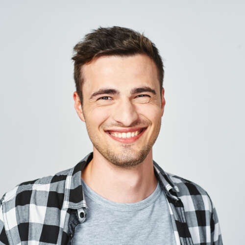 man with check shirt & white teeth smiling