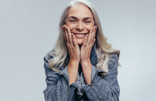 Blonde women with white teeth smiling holding her face