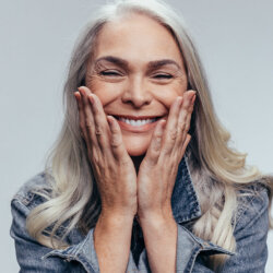 Blonde women with white teeth smiling holding her face close up