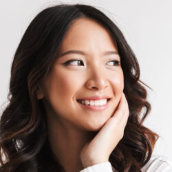 Girl with white teeth smiling holding her left chin close up